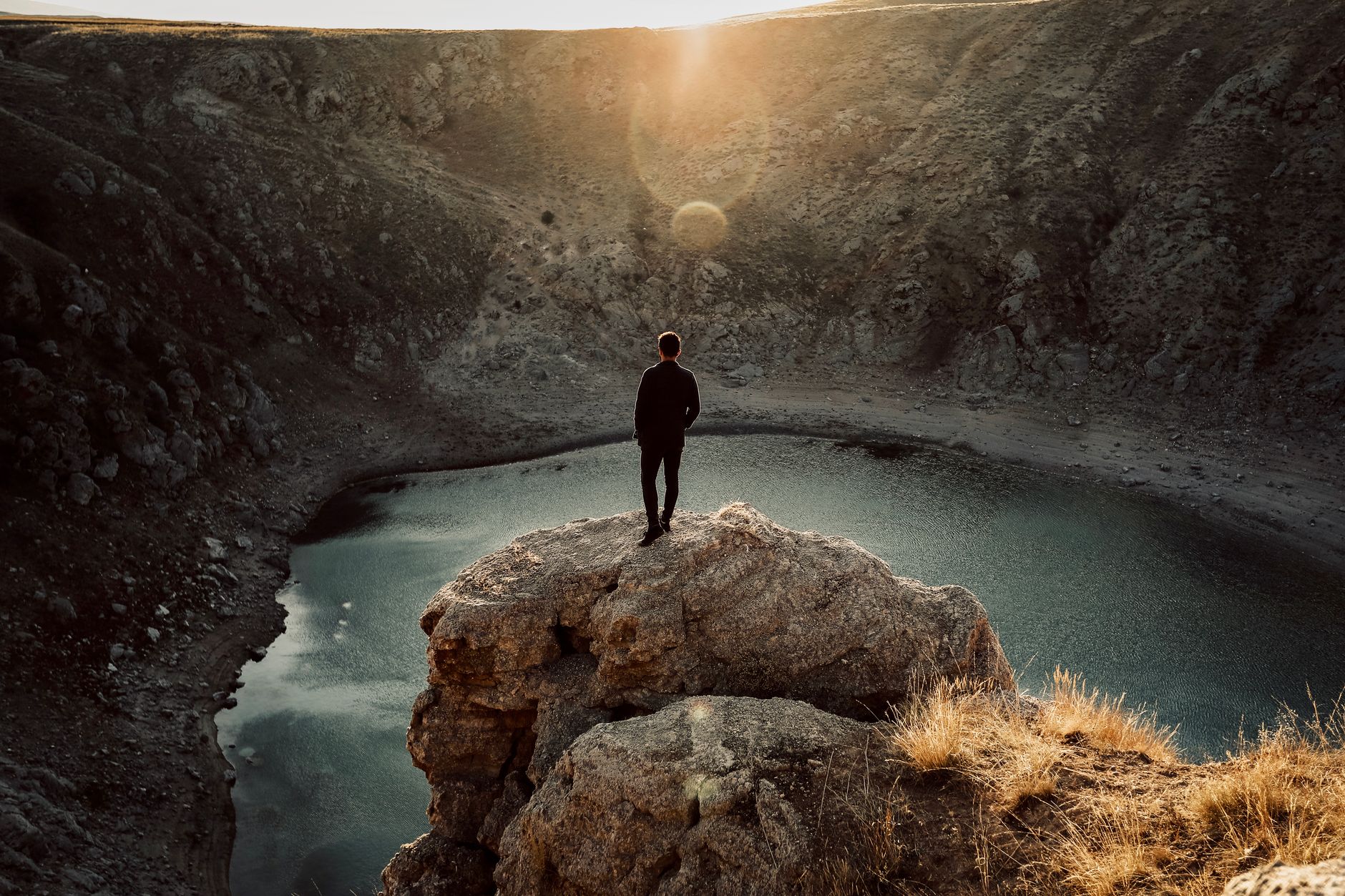 man overlooking a lake from a cliff